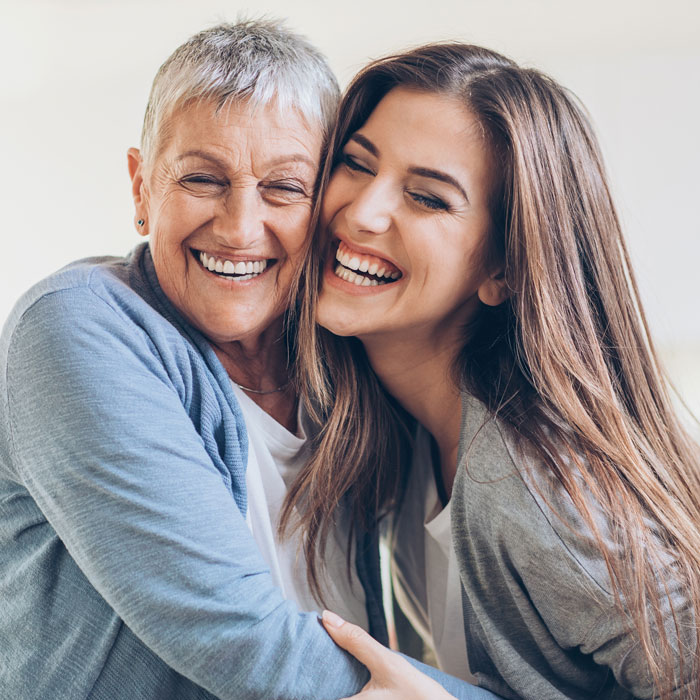 senior mom and adult daughter laughing