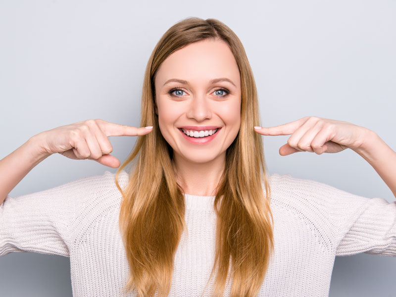 woman smiling pointing at her teeth