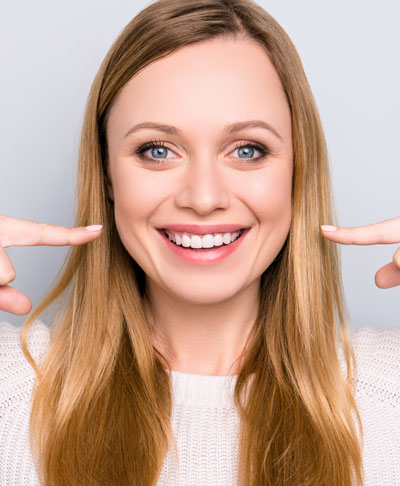 woman smiling pointing at her teeth